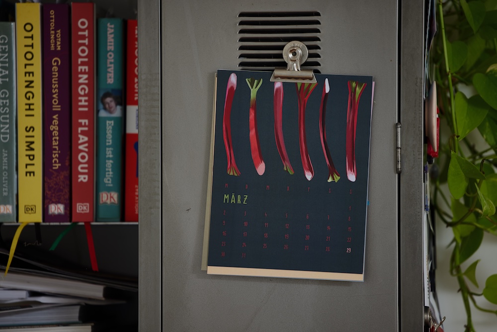 aufgehängter kalender, monat märz, er zeigt 6 ehabarber stangen auf dunkel türkisenem hintergrund