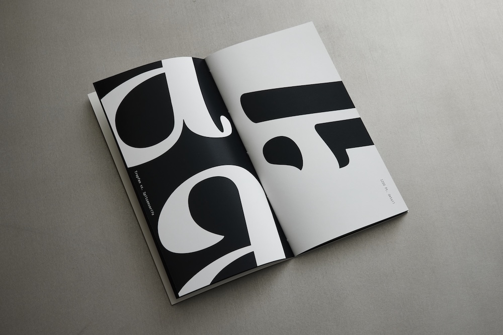 aufgeschlagenes specimen welches ausschnitte der buchstaben a und i zeigt, das a ist weiß auf schwarz und das i anders herum